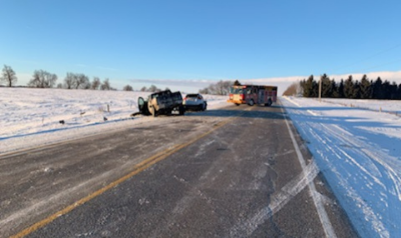 A Roadway is blocked by an emergency vehicle in the distance, with a pick-up truck and car off the left side of the road