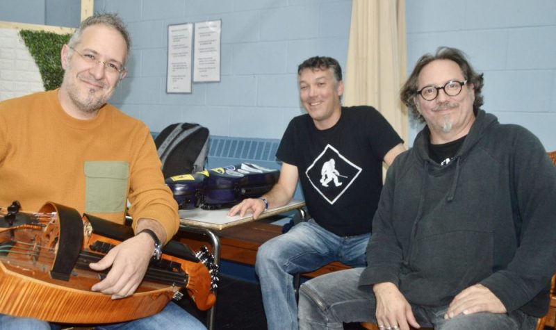 Trois hommes assis avec des instruments de musique.