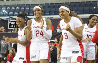 People in white and red basketball jerseys smiling and inside a stadium.