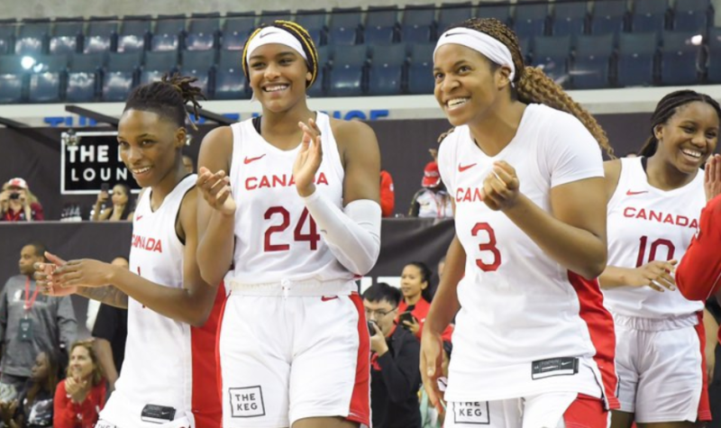 People in white and red basketball jerseys smiling and inside a stadium.