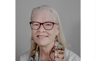 A professional headshot of Carla Neale against a grey background.