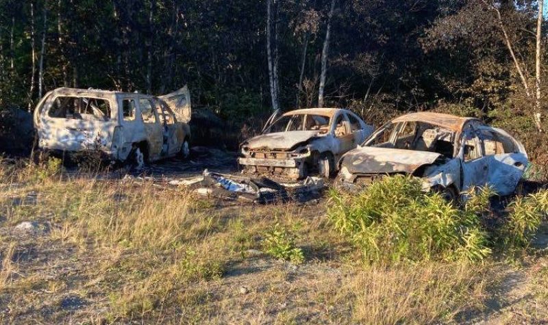 Three burned out cars in a field