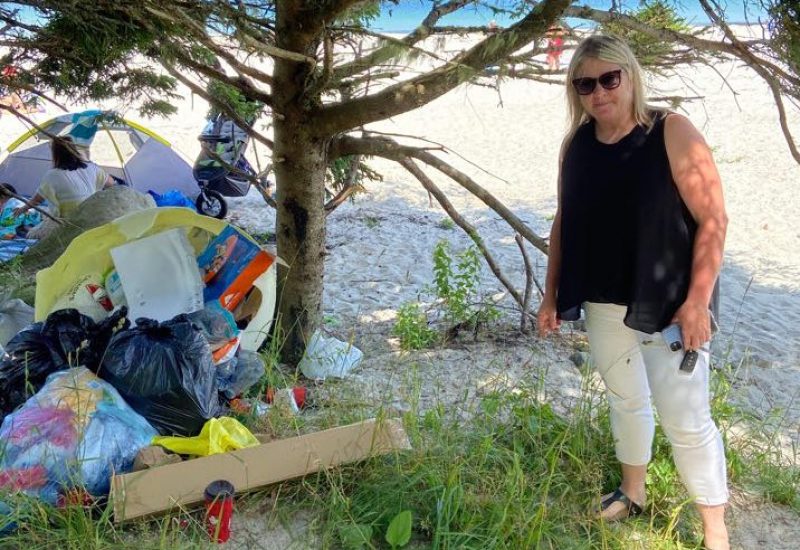 A photo of Queens-Shelburne MLA Kim Masland stands next to a pile of garbage at Carters Beach.
