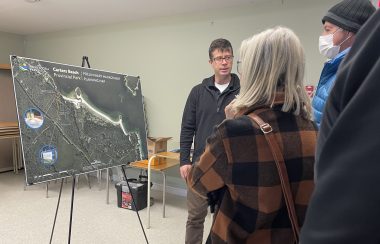 A presenter stands in front of an display depicting a preliminary planning map for Carters Beach