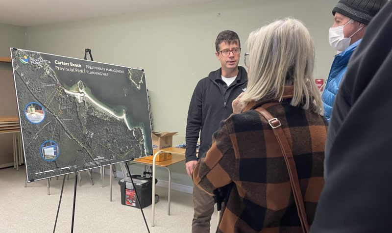 A presenter stands in front of an display depicting a preliminary planning map for Carters Beach