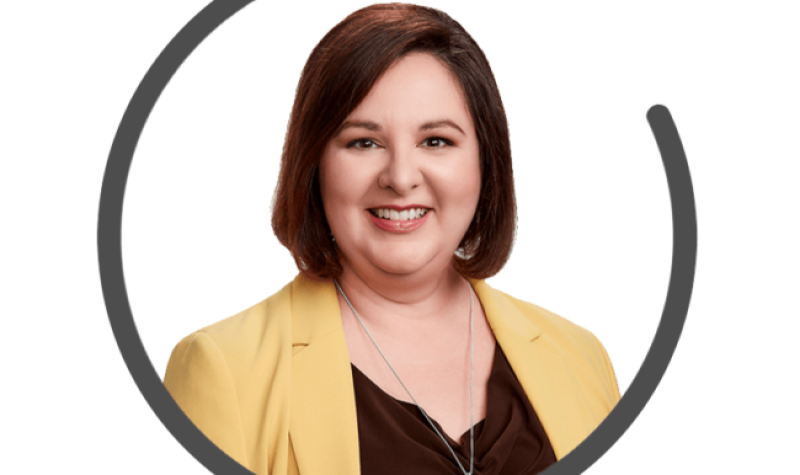 Catherine Bate, CEO of Ad Standards, wears a yellow blazer over a black shirt, has short dark hair, and a big smile.rs,