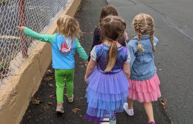 A group of young children walk down a sidewalk