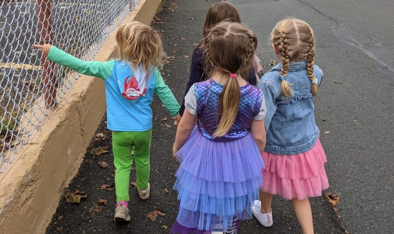 A group of young children walk down a sidewalk