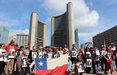Un grupo de chilenos con banderas y carteles frente al City Hall en Toronto.