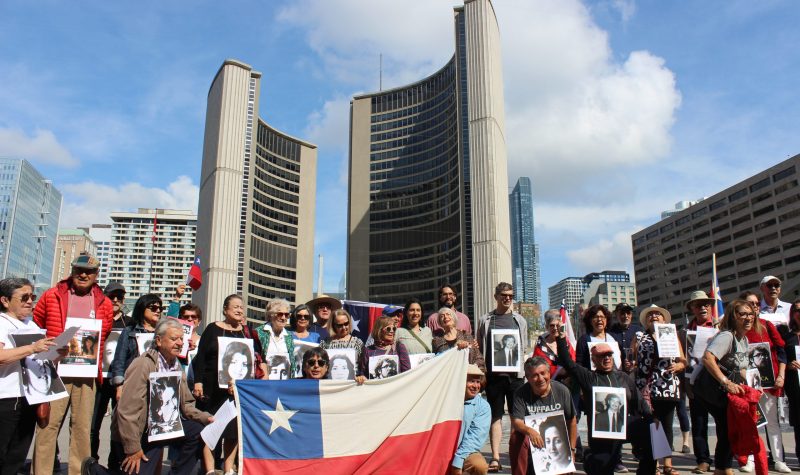 Un grupo de chilenos con banderas y carteles frente al City Hall en Toronto.