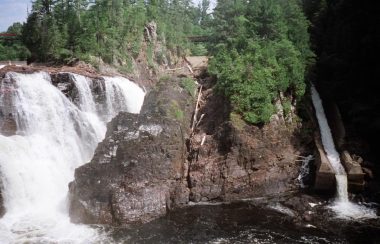 A photo of the Chutes Coulonge, a large waterfall with a timber slide on the right.