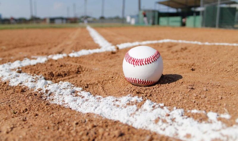 Terrain de baseball vu au ras du sol sur la terre battue. Une balle de baseball trône devant l'objectif de l'appareil photo.