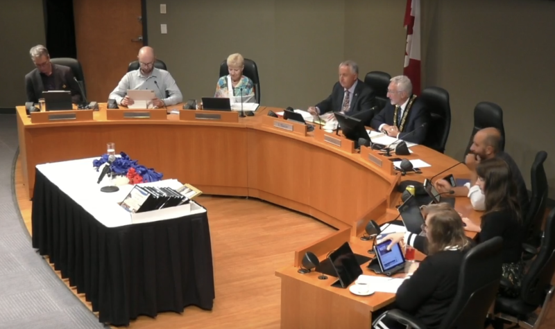 Seven people sit around a semi-circle wooden table as Nanaimo city council meets