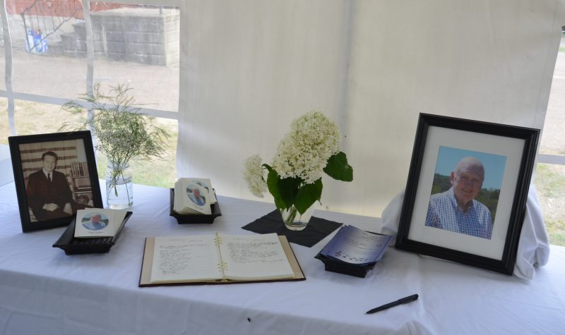 A memorial for Cletus Ferrigan at his celebration of life, featuring two photos and a guest book.