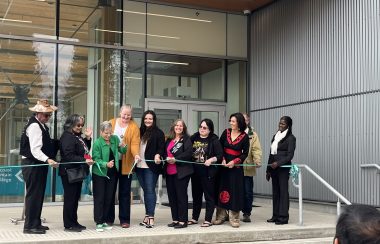group of 10 people out side a newly renovated building for a ribbon cutting ceremony