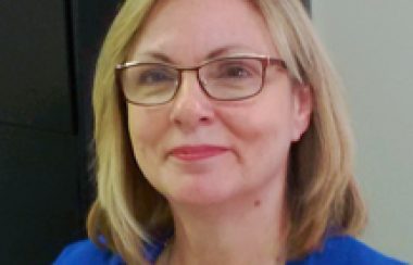 A headshot of Colleen Lariviere wearing a blue top and glasses.