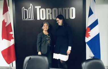 deux femmes debout sous le sigle de la ville de Toronto