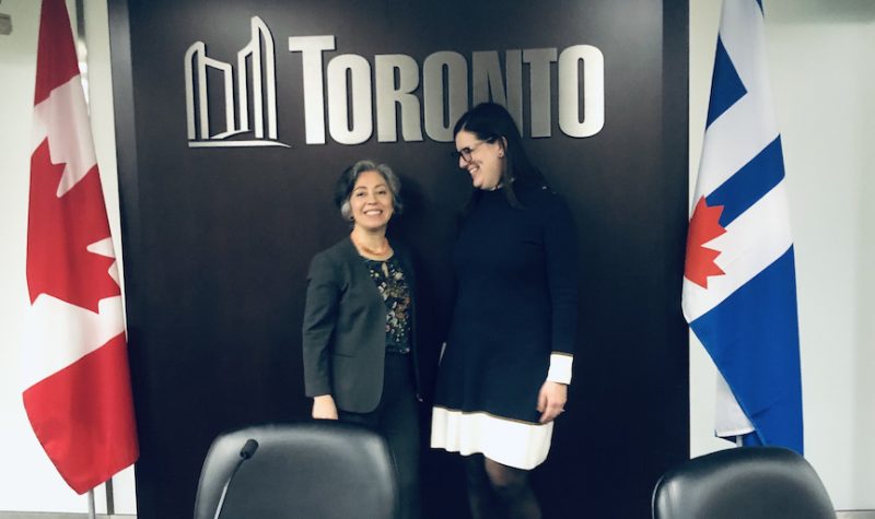 deux femmes debout sous le sigle de la ville de Toronto