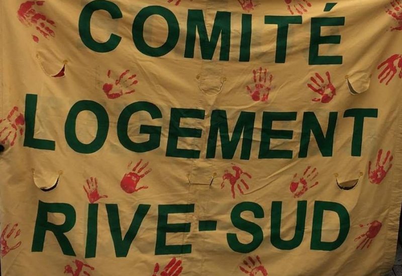 Une bannière au fond jaune sur laquelle il est inscrit Comité Logement Rive-Sud en lettre majuscule verte.