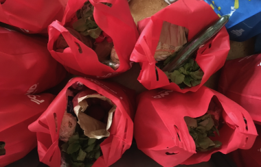 Red reusable grocery bags full of fresh produce, from above