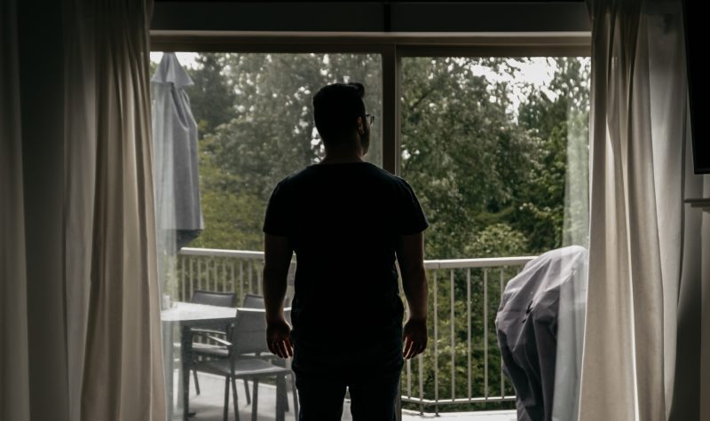 Un homme regardant sa terrasse par la fenêtre