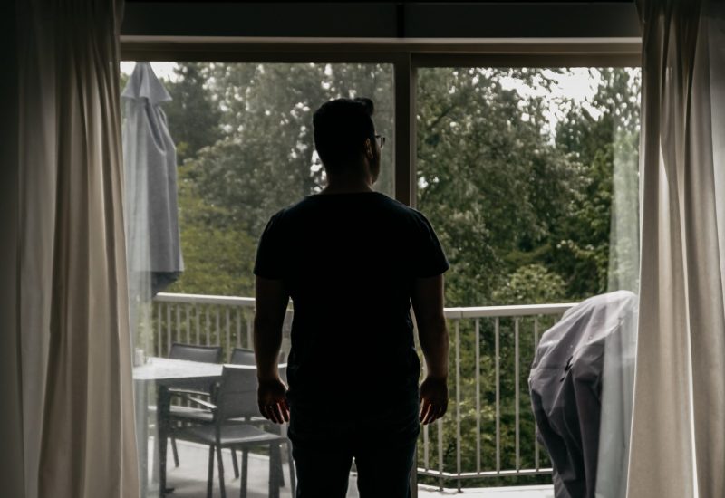 Un homme regardant sa terrasse par la fenêtre