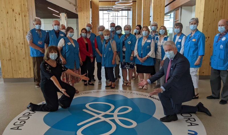 Les bénévoles sont debout autour d'un rond bleu écrit dessus: Association des bénévoles de l'Hôpital Monfort