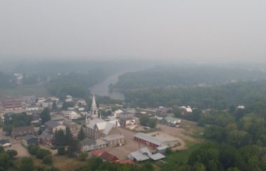 A birds eye view of a town blanketed in forest fire smoke.