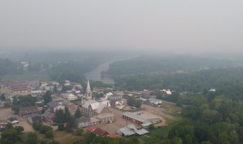 A birds eye view of a town blanketed in forest fire smoke.