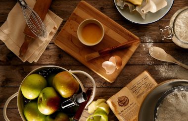 Plusieurs articles de cuisine sur une table avec ddes pommes et du beurre