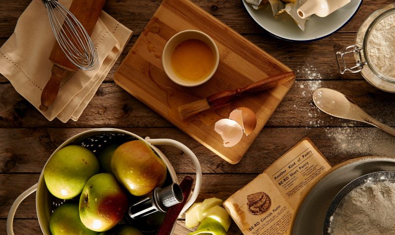 Plusieurs articles de cuisine sur une table avec ddes pommes et du beurre