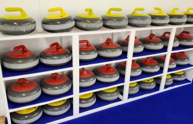 Curling stones sit in neatly lined rows on shelves