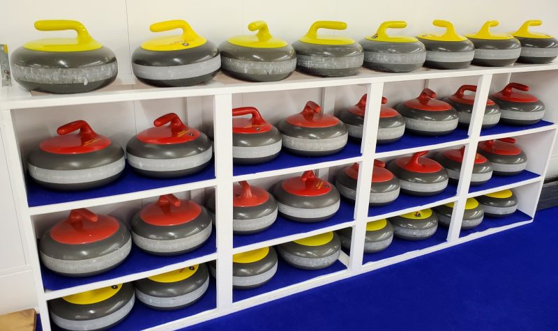 Curling stones sit in neatly lined rows on shelves