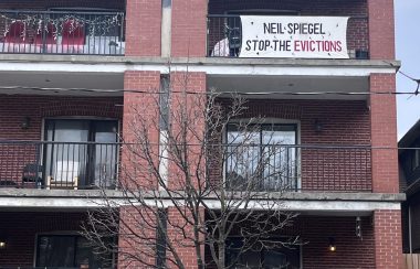 A red brick building with white banners with black text on some floors.