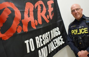 Constable Shawn Evans devant le drapeau du projet D.A.R.E.