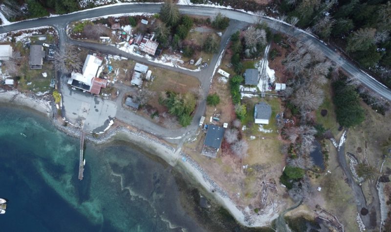 Aerial photo of water front land and a dock connected.