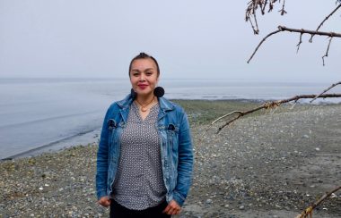 A woman stands on a misty beach in Haida Gwaii