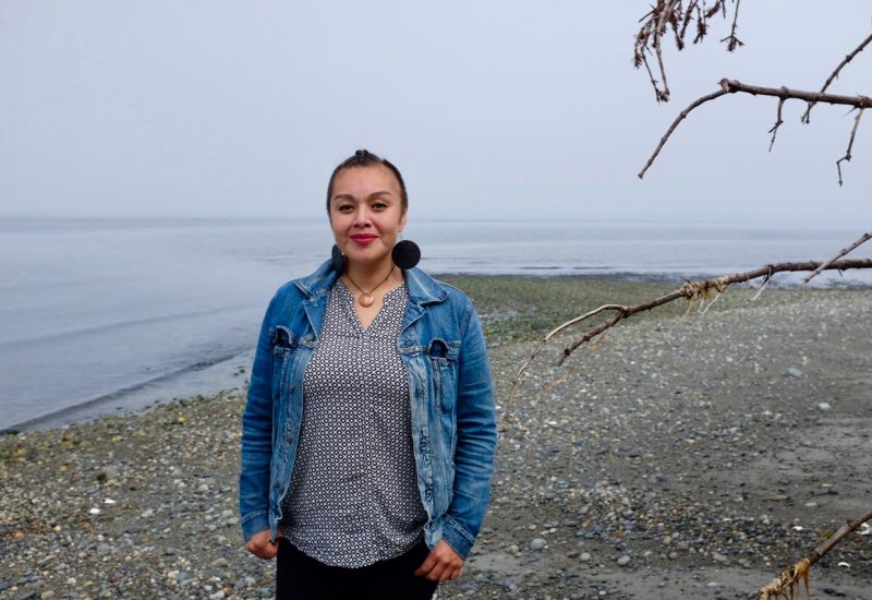 A woman stands on a misty beach in Haida Gwaii