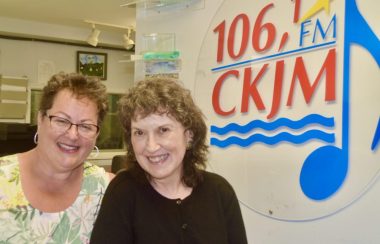 Deux dames en avant du logo de Radio CKJM.