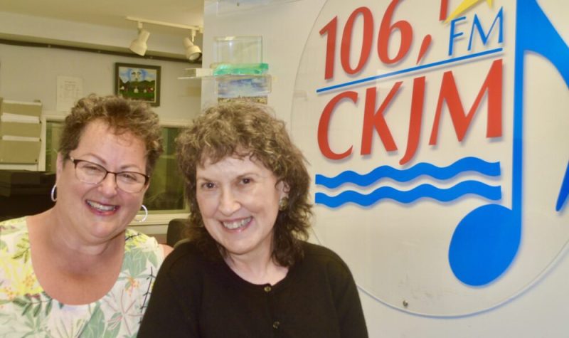 Deux dames en avant du logo de Radio CKJM.