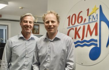 Deux hommes portant des chemises bleu en avant du logo de Radio CKJM.
