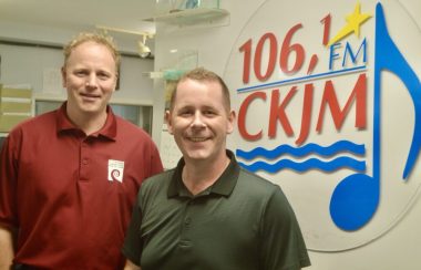 Un homme portant un chandail rouge et un homme portant un chandail vert en avant du logo de Radio CKJM.
