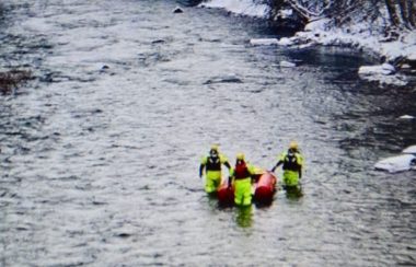 Trois hommes dans une rivière avec un canot de sauvetage.