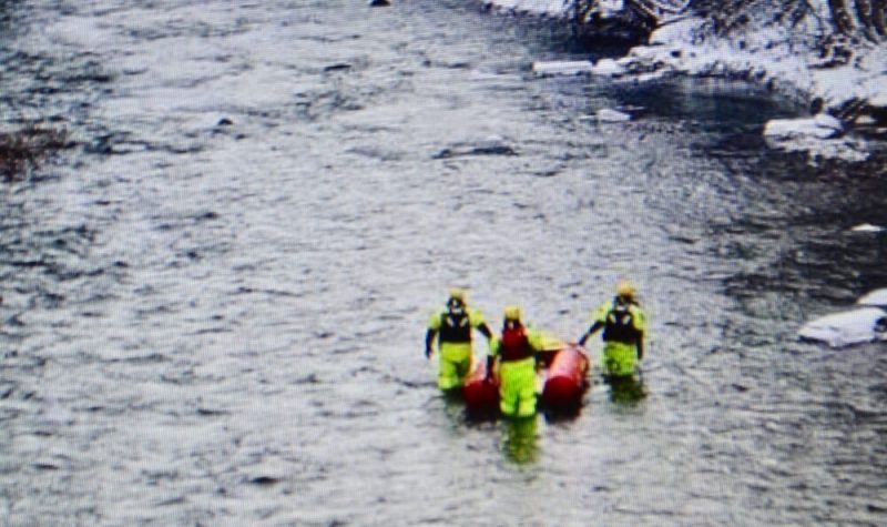 Trois hommes dans une rivière avec un canot de sauvetage.