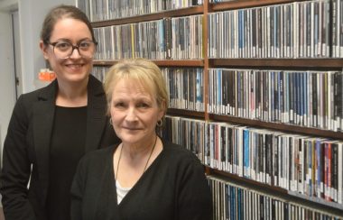 Deux dames habillées en noir déboutés en avant d'une étagère de disques.