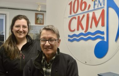 Un homme et une femme en avant du logo de Radio CKJM.