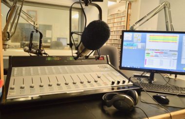 Console, micro, ordinateur et écouteurs dans un studio de radio.