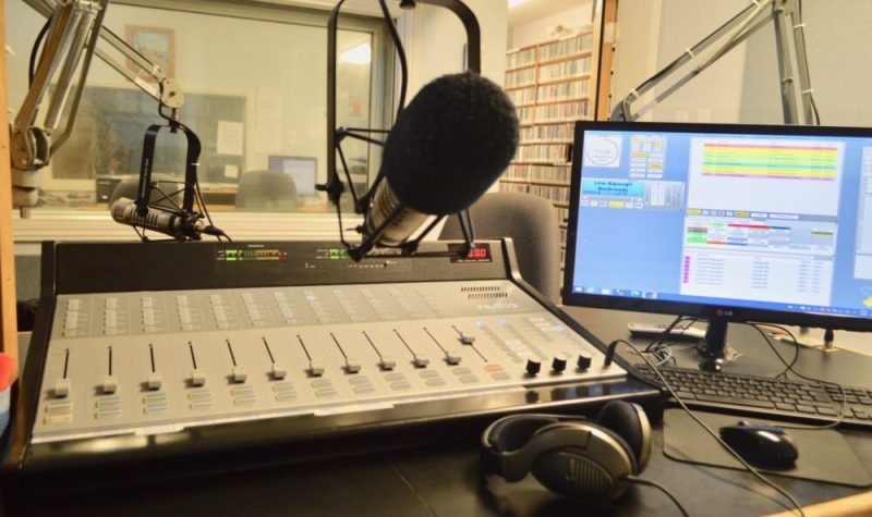 Console, micro, ordinateur et écouteurs dans un studio de radio.