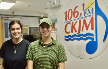 Deux jeunes filles en avant du logo de Radio CKJM.