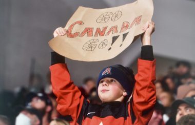 Un jeune garçon portant un chandail rouge et tenant une affiche.